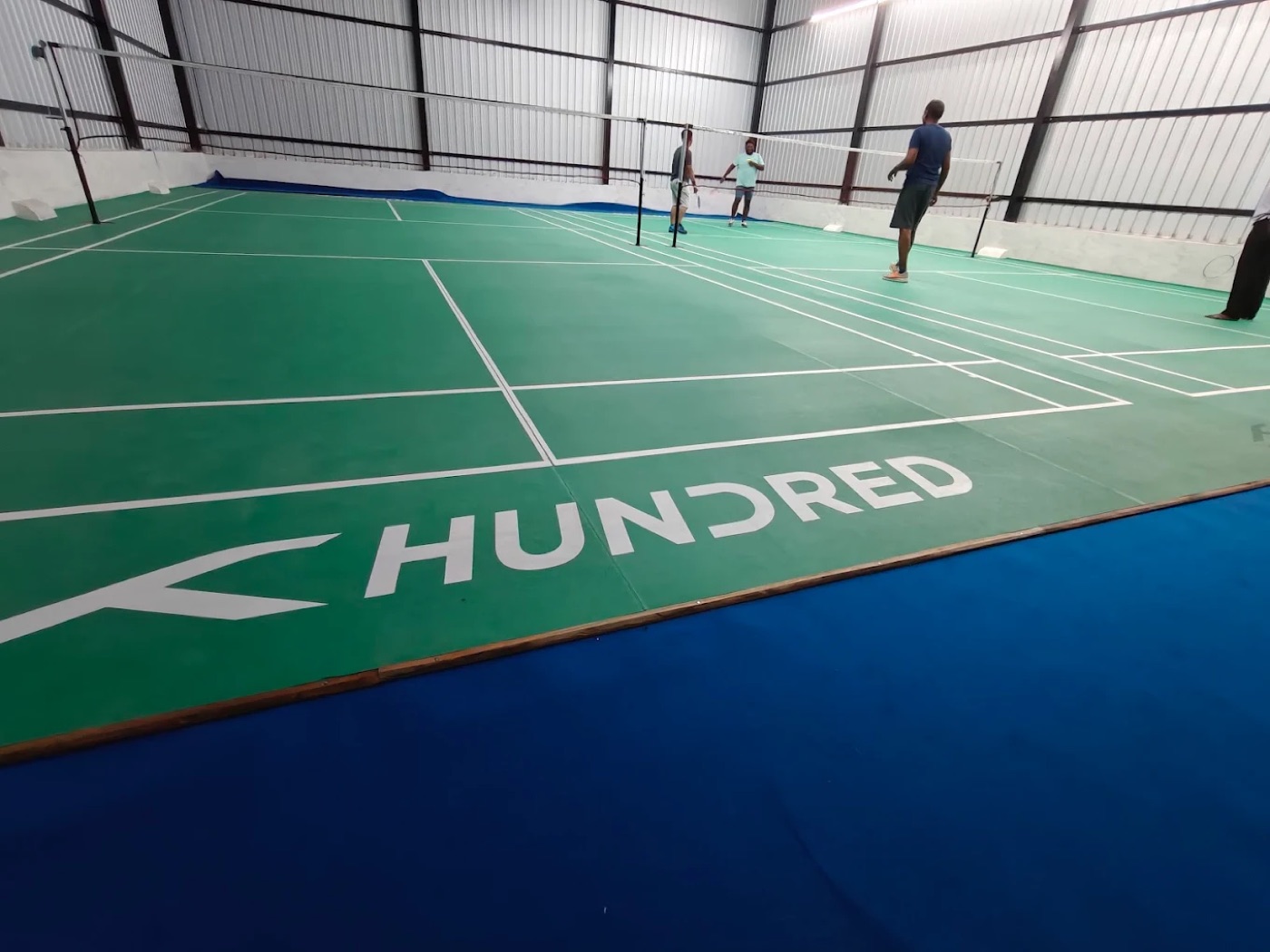 Green badminton court flooring and court lines at Idigarai