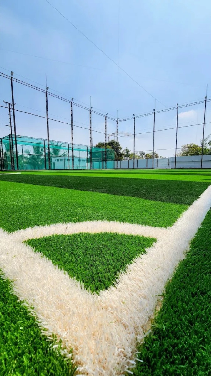 Corner of the football and box cricket turf at Sportiv Bloc, with floodlit nets behind